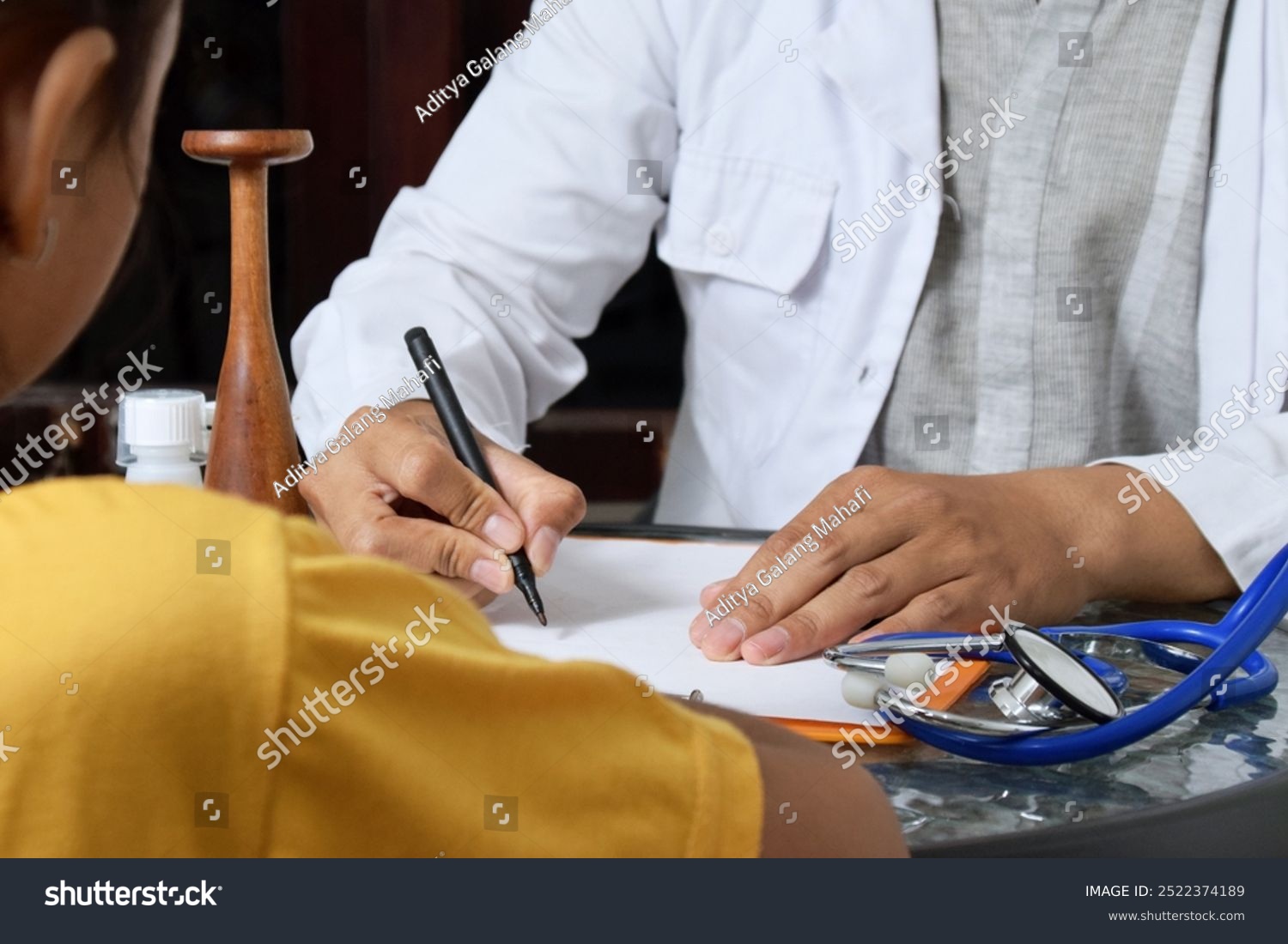 stock-photo-a-doctor-is-taking-notes-regarding-a-health-consultation-for-a-young-girl-this-consultation-is-to-2522374189